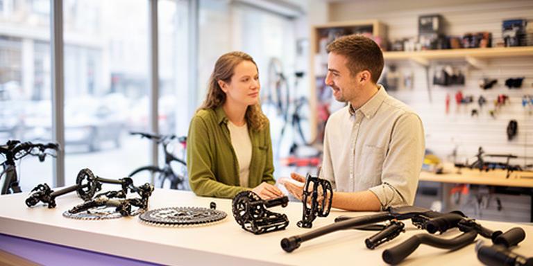 Beratung zu Fahrradteilen an einer Verkaufstheke in einem hellen Fachgeschäft