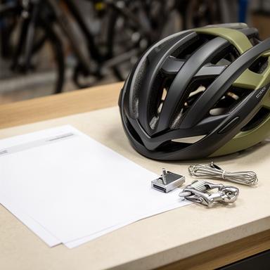 Fahrradhelm und Zubehör neben gedruckten Bestellunterlagen auf einem Verkaufstisch